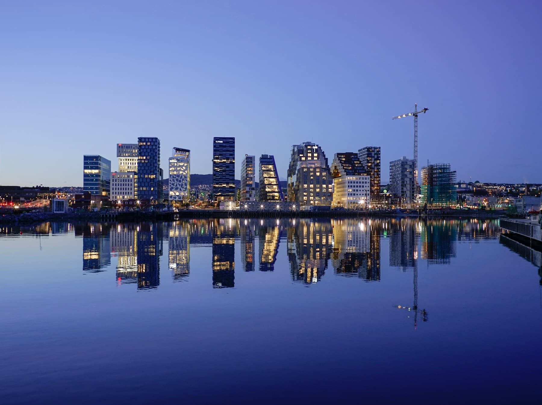 Oslo’s illuminated Barcode skyline reflected in the waterfront at blue hour